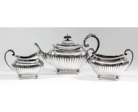 An Edward VII silver rectangular three piece tea service with reeded mounts, part reeded domed cover and body, leaf capped C-