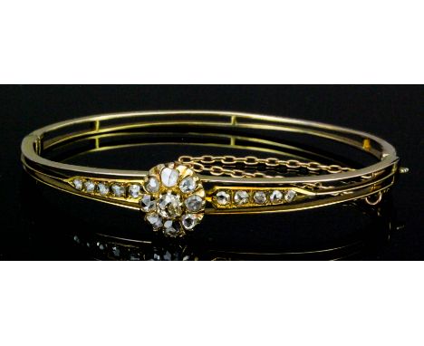 A late Victorian gold coloured metal mounted diamond set stiff pattern bangle, the face with a central diamond set flowerhead