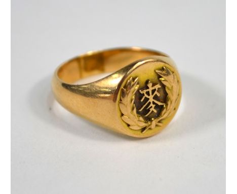 A yellow metal signet ring with leaf and Chinese character decoration, size S/T, stamped 18, approx 9.5g all in