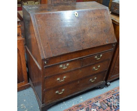 A Georgian oak bureau, the fitted interior of niches and drawers over a slide top storage well and three long graduated drawe