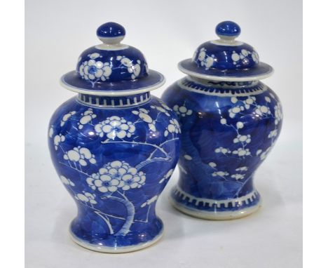 A matched pair of 20th century Chinese porcelain blue and white baluster vases and covers, decorated with prunus on cracked i
