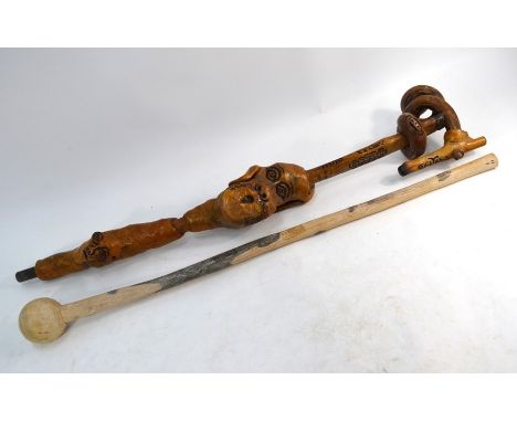 A carved wood walking stick of unusual and ornate design, with incised decoration, curled root handle and grotesque masks to 