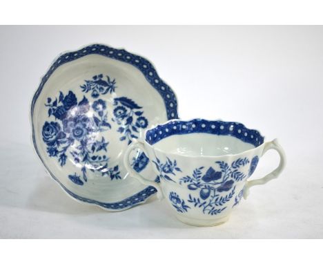 An 18th century first period Worcester blue and white trembleuse cup and saucer decorated with flowers and moths, underglaze 