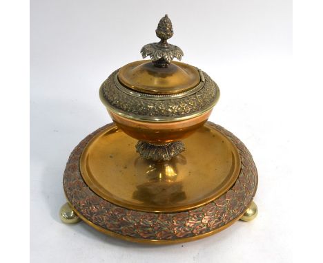 A 19th century Continental circular brass and copper inkstand, the hinged top with pineapple finial, on bun feet 19cm diam