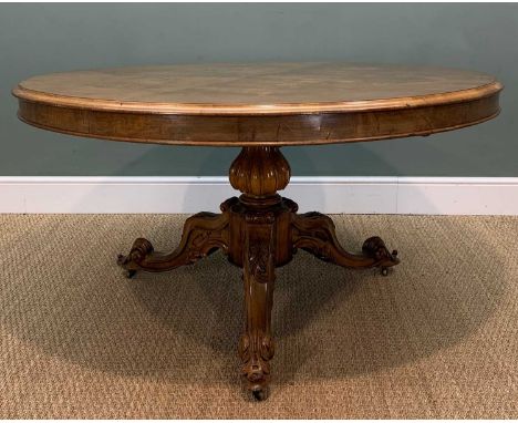 MID-VICTORIAN WALNUT BREAKFAST TABLE, circular tilt-action quarter veneered top, ornately carved tripod base, brass castors, 