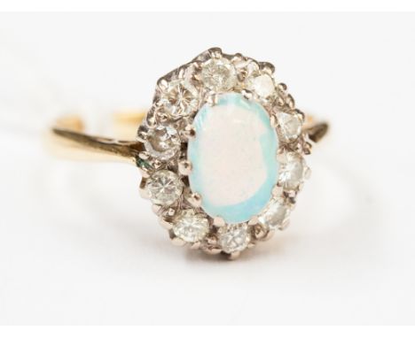 An opal and diamond ring cluster with oval opal to the centre and ten diamonds to the outer border 