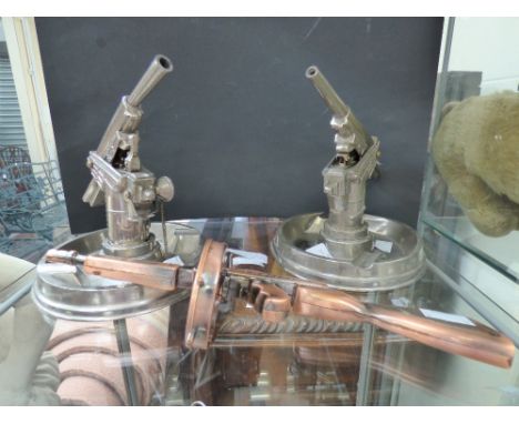 An pair of table cigarette lighters with ashtray bases, the lighters in the form of machine guns; together with a similar tab