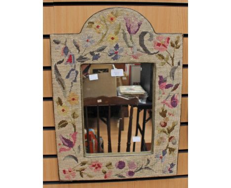 A wall mirror set in a tapestry woolwork frame 