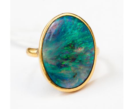 **RE-OFFER MAY 300/500**A black opal ring set oval cabochon with green, blue and purple fire, in rub over gold setting, 22ct 