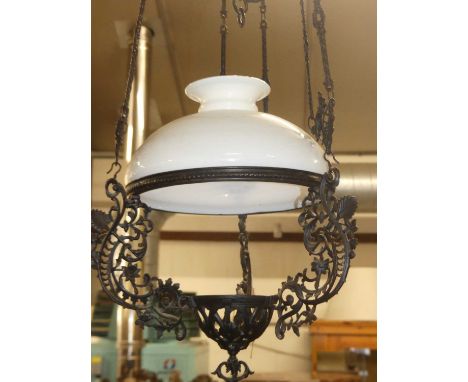A pierced floral decorated and black painted metal hanging ceiling light, having a domed milk glass shade