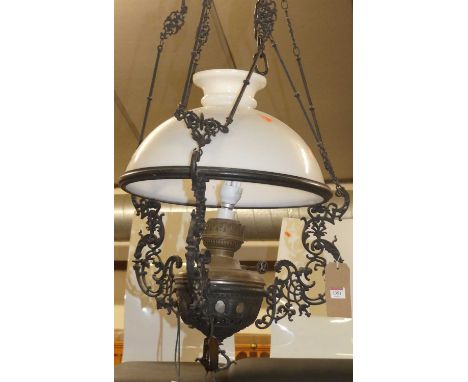 A large pierced floral decorated and black painted metal hanging ceiling light, having a domed milk glass shade
