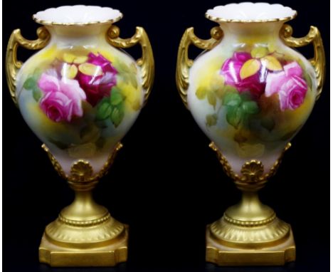 Pair of Royal Worcester twin handle vases with handpainted blooming rose decoration, twin gilt handles and pedestal bases. Ci