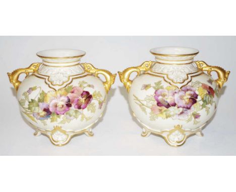 Pair of Royal Worcester blush ivory vases with handpainted pansy decoration, ornate gilt dolphin handles, on four feet. Circa