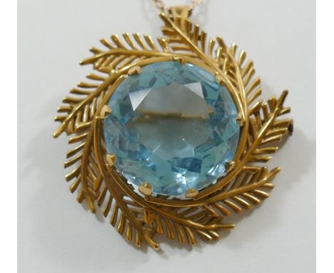 A yellow metal blue paste set pendant brooch, the circular stone with fern surround, unmarked, 11.5g gross, and chain, 62.5cm