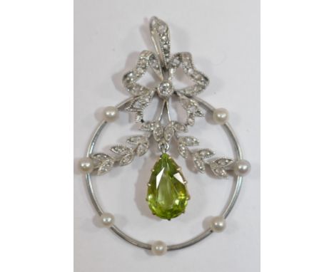 An Edwardian diamond and peridot openwork pendant in the form of a ribbon and swags, with pear shaped peridot drop to the cen
