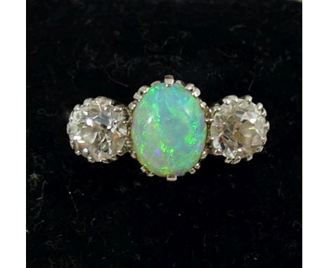 An early 20th century opal and diamond three stone ring, the oval opal cabochon set between two old cut diamonds each approxi