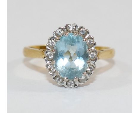 An 18 carat gold diamond and aquamarine oval cluster ring, the oval mixed cut aquamarine in claw setting within 12 round bril