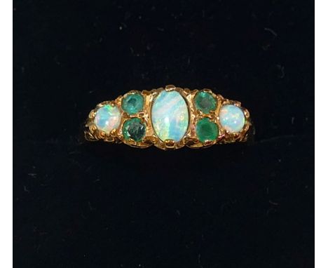 A 9 carat gold opal and emerald Victorian style carved half hoop ring, the three oval opal cabochons interspersed with two pa