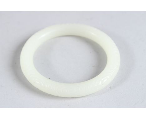 A CHINESE WHITE JADE CARVED BANGLE. 3.25ins diameter.