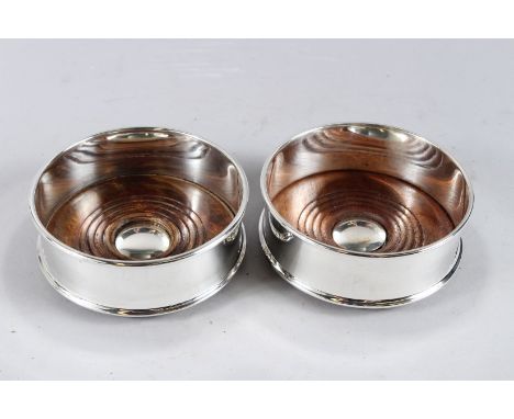 A PAIR OF PLAIN CIRCULAR PLATED WINE COASTERS with wooden bases.