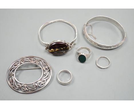 A 1970's silver and oval quartz set bangle, two other white metal bangles and three assorted rings.