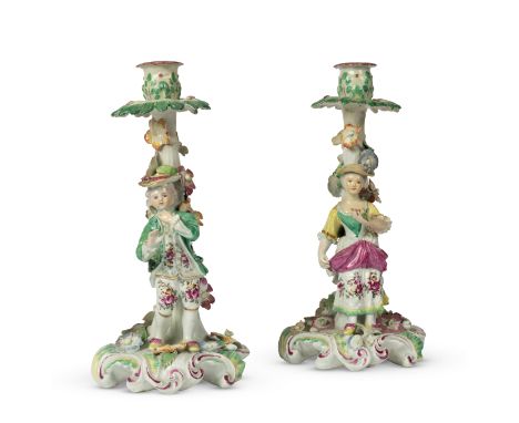 A pair of Derby 'Pale Family' figural candlesticksCirca 1758-60Modelled as a boy and girl, each standing before a trunk appli