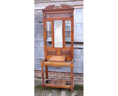 An Edwardian walnut hall stand with pierced carved and spindle decoration, fitted mirror over glove box, on turned supports, 