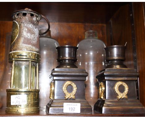 An Ackroyd &amp; Best brass and metal miner's lamp and two storm lamps with cold cast bases