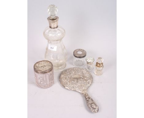 A silver collared decanter, a floral swag decanter, a silver and enamel topped scent bottle, a white metal mirror and other i