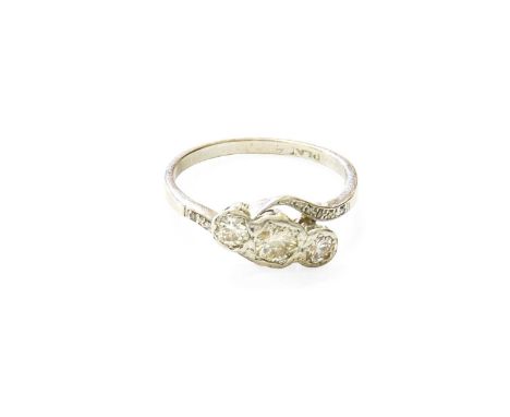 A Diamond Three Stone Ring, the graduated round brilliant cut diamonds in white rubbed over settings, to diamond set twist sh
