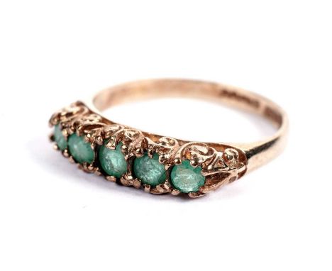 A five-stone emerald ring, in 9ct yellow gold scrolling mount and shank, ring size O, 2.1g gross.