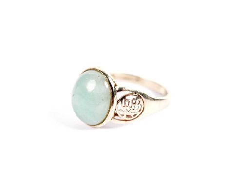 A Chinese style jadeite dress ring, with oval jadeite cabochon on pierced shoulders, in yellow gold, stamped “14k 585”, "Hong