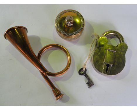 A small copper hunting horn of sprung form together with an outlined brass pill box with embossed border and finial in the fo