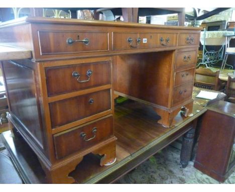 A reproduction yew wood veneered kneehole twin pedestal writing desk in the Georgian style with inset green leather panelled 