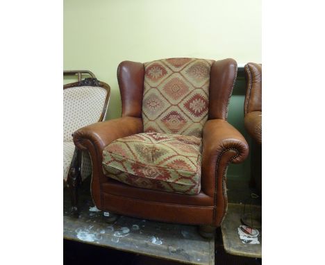 A good quality contemporary armchair, the wing back over scrolled arms, in simulated brown leather finish, with Kelim cushion