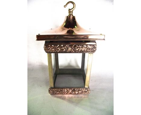 A polished copper and brass ceiling lantern of squared form with glazed sides, the copper mounts embossed with foliate detail