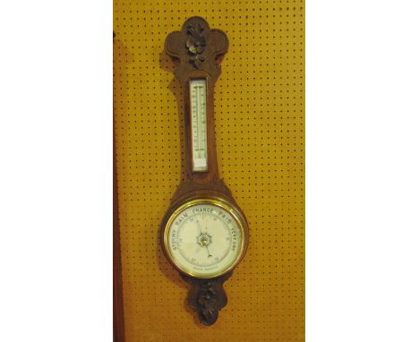 An Edwardian oak aneroid barometer with ceramic dials and carved casework