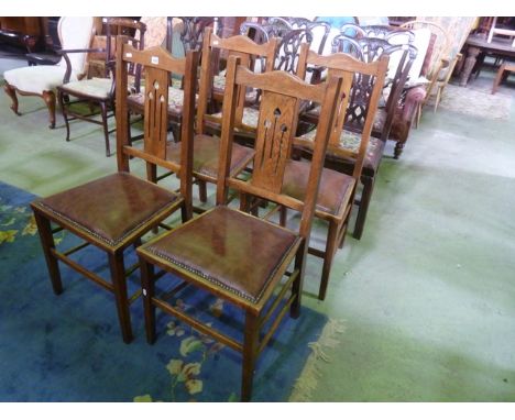 A set of four Edwardian Arts & Crafts style oak dining chairs with central pierced arrow head splats over brown leather uphol