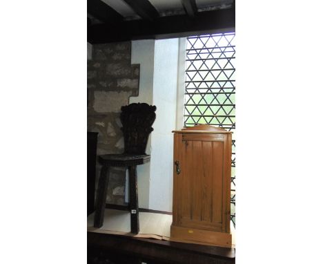 An Edwardian stripped pine bedside cupboard with shallow raised architectural back over a rectangular panelled door set on a 