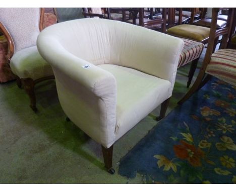 An Edwardian tub chair with rolled arms, simply upholstered in white calico and raised on square tapered forelegs with brass 
