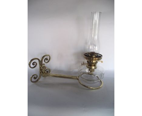 An antique oil burning lamp with clear glass fount and Eltex burner, set within a good quality scrolling adjustable brass wor