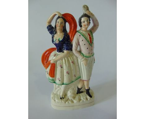 A 19th century Staffordshire figure group of a pair of theatrical characters, she dancing with an orange sash, he holding a d