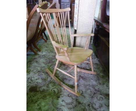 A Windsor style stick back rocking chair with central pierced and shaped splat, over open arms, solid seat, turned supports a