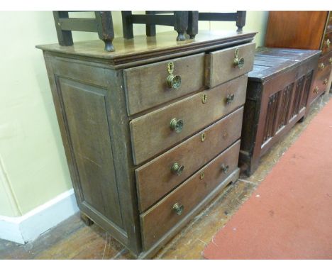 A Georgian oak country made chest of three long and two short drawers with embossed brass plate handles and escutcheons, rais