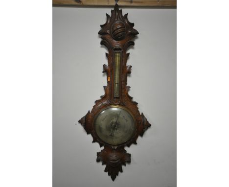 A VICTORIAN BLACK FOREST WHEEL BAROMETER, the frame with leaf scrolls surrounding thermometer and brass dial that appears lat