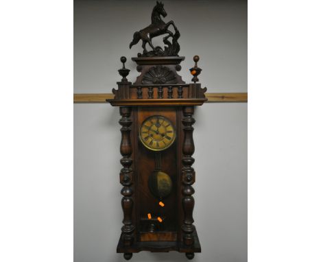 A LATE 19TH CENTURY WALNUT VIENNA WALL CLOCK, with a resin horse pediment, turned pillars to the doors, enclosing a dial with