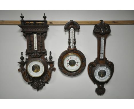 A LATE 19TH CENTURY FRENCH CARVED WALNUT ANEROID BAROMETER, height 90cm and an oak aneroid barometer, and a carved wood anero
