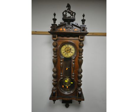 A LATE 19TH CENTURY VIENNA WALL CLOCK, with a resin horse pediment, turned pillars to the doors, enclosing a dial with Roman 