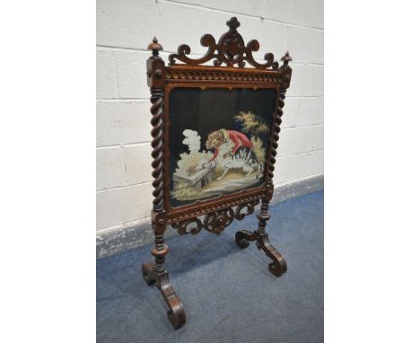 A VICTORIAN WALNUT FIRESCREEN, with open scrolls and central shield, turned finials, barley twist uprights, flanking a glass 