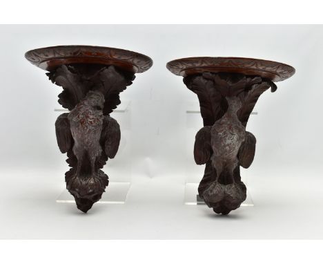 A PAIR OF LATE 19TH CENTURY BLACK FOREST CARVED OAK WALL BRACKETS, the demi-lune shelf over a game bird with outstretched win